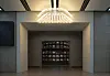 Modern lobby corridor with a lit chandelier and a recessed wall display in a neutral interior.