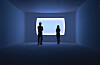 Two people in silhouette stand in a dim blue room facing a bright rectangular opening.