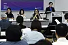 Museum director speaks at a press briefing while panelists sit behind a table and attendees watch in the foreground.