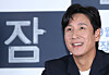 Lee Sun-kyun smiles at a press event with the film title 'Sleep' visible in the background.