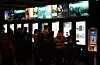People line up at illuminated ticket kiosks inside a Seoul movie theater.