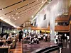 People gathered in a modern lobby with wood ceilings, bright lighting, and lounge seating.