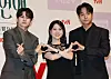 Three actors pose on stage making heart gestures at a tvN drama production event in Seoul.