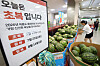 Watermelons stacked in a Lotte Mart store beside a sign advertising a Chobok limited sale.