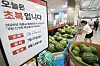 Watermelons stacked in a Lotte Mart store beside a sign advertising a Chobok limited sale.