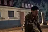 A soldier crouching near a building with Korean signs lit in the background at night.