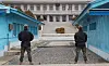 Two South Korean soldiers stand guard between blue buildings at Panmunjom.