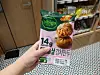 Hand holding a Bibigo frozen dumpling package in a grocery store aisle.