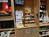 Grocery store self-checkout kiosk with payment terminal, snack display, and nearby product shelves.