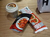 Packaged snack items and a dessert cup sit on a wooden table.