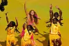 Shakira sings onstage with dancers in yellow during the World Cup final halftime show.