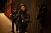 Three armed tactical personnel move through a narrow industrial corridor at night.