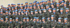 Rows of uniformed peacekeepers in blue helmets pose for a group photo indoors.