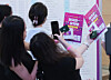 International students take photos of pamphlets at the Job Fair for International Students in Busan on Aug. 19, 2025.