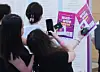 International students take photos of pamphlets at the Job Fair for International Students in Busan on Aug. 19, 2025.
