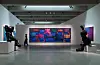 Modern museum gallery with a bright neon artwork, sculptures, and visitors in a spacious exhibition hall.