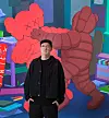 Man standing in front of two large red inflatable figures in a colorful indoor display.