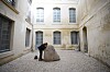 A visitor stands beside a large stone sculpture in a courtyard exhibition space at Lee Ufan Arles.