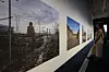 People viewing large landscape photographs displayed along a gallery wall in a museum exhibition.