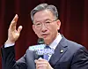 Justice Minister Jung Sung-ho speaks into a microphone at a talk concert, raising one hand.
