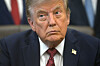 President Donald Trump seated in the Oval Office of the White House, wearing a suit and tie.