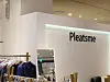 Boutique interior with Pleatsme branding, clothing racks, and a mirror.