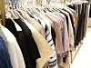 Clothing rack with assorted garments hanging on white hangers in a retail setting.