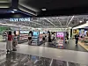 Shoppers inside a modern grocery and retail store with refrigerated displays and product shelves.