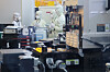 Trainees in cleanroom suits stand beside semiconductor processing equipment inside a fab.