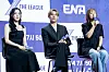 Three people seated on stage at a promotional event with ENA and The League signage behind them.