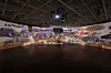 Wide view of an empty indoor arena with stage equipment and seating.