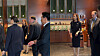 People standing and talking in a modern office lobby with wood paneling and display shelves.