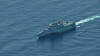 A gray USS Cincinnati warship moves across calm blue water in the South China Sea.