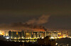 Night view of Kyiv with smoke rising above illuminated buildings after a missile attack.