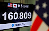 Monitor in Tokyo shows the yen exchange rate at 160.809 per dollar next to U.S. and Japanese flags.