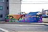 A colorful abstract mural painted on a wall next to an empty urban street.
