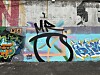 A weathered wall covered with colorful graffiti and layered street art.