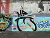 A weathered wall covered with colorful graffiti and layered street art.