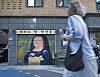 Blurred pedestrian passing a mural-painted storefront on a city street.