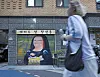 Blurred pedestrian passing a mural-painted storefront on a city street.