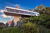 Modern elevated bridge above lush green plants and trees on a sunny day.