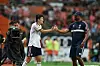 Vincent Kompany and Kim Min-jae shake hands on the sideline during a football match.