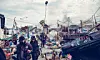 Crowded fishing harbor with boats, nets, and workers along a busy dock.