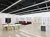 Bright modern exhibition room with display tables, wall panels, and a central display area.
