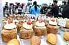 Trays of cream-topped pastries and bread are displayed at a crowded coffee and bakery fair.