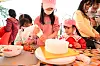 Children and adults making strawberry desserts at a festival table.