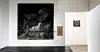 Minimalist gallery space with two black-and-white artworks on white walls and a dark floor.