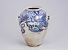 Blue-and-white ceramic vase decorated with landscape designs on a gray background.
