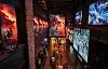 Cinema lobby with large screens showing 'Odyssey' promotional visuals and visitors walking below.