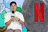Na Young-seok holds a microphone beside a large Netflix logo at a Seoul media event.